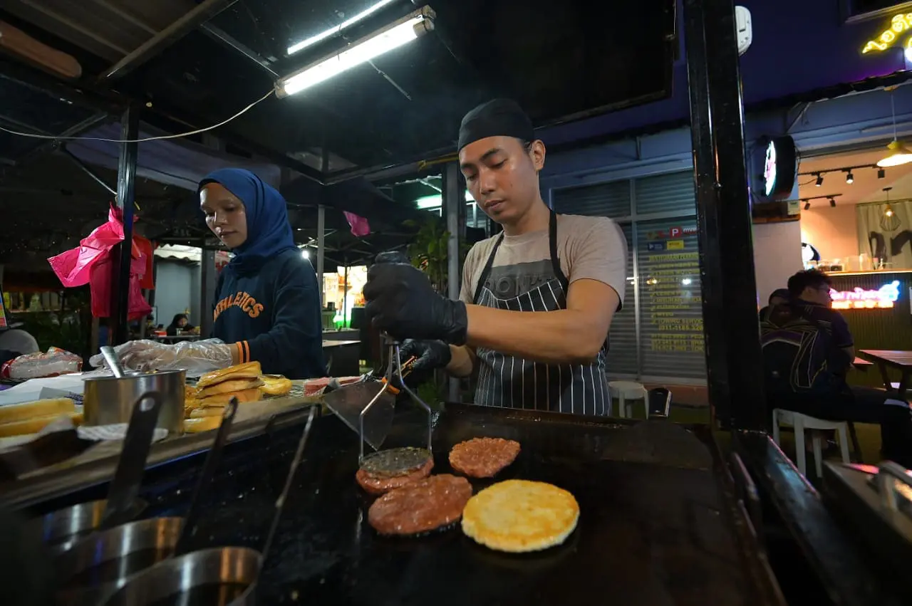 Msian making burgers at his stall