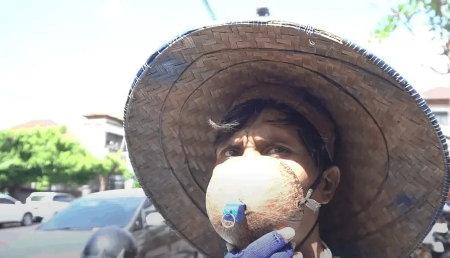 Indonesian Men, Nengah Budiasa wears coconut shell as his surgical mask