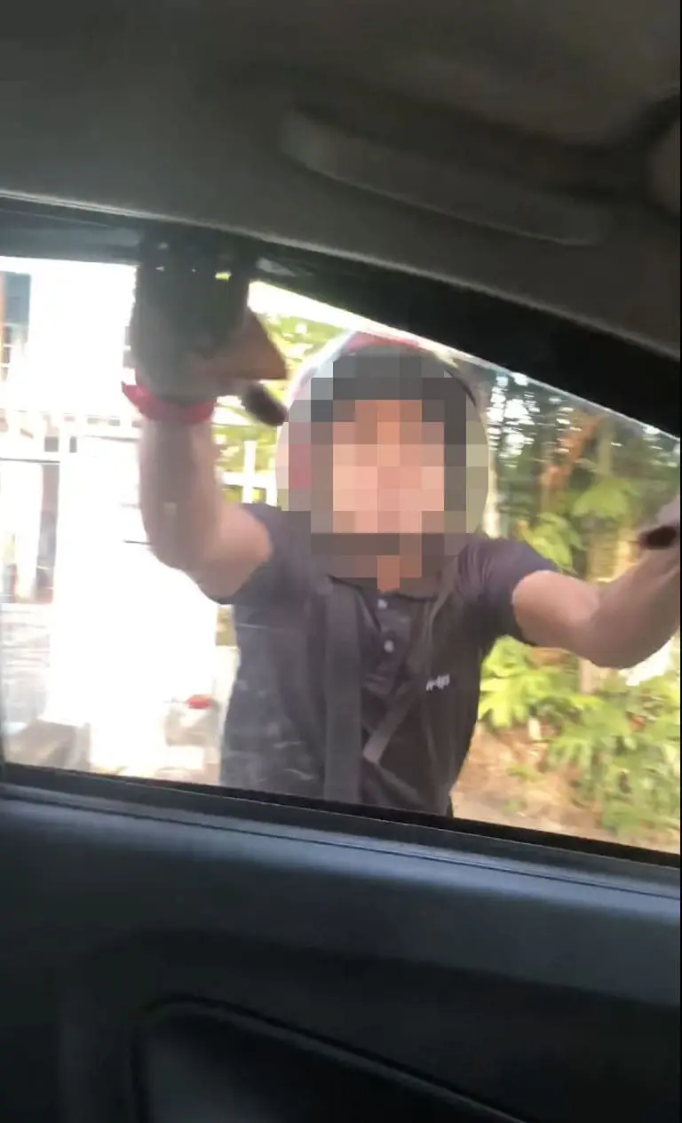 Raging man breaking car window
