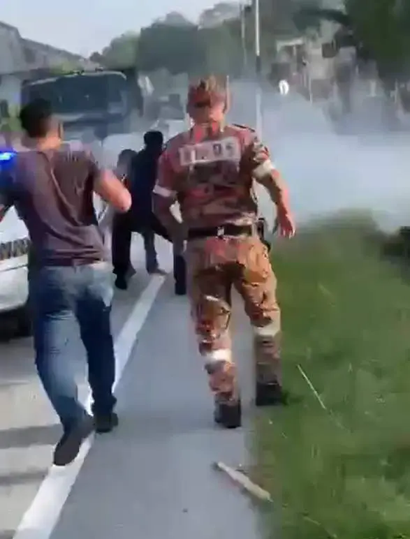 Man runs amok, swinging a parang while standing on top of a police car