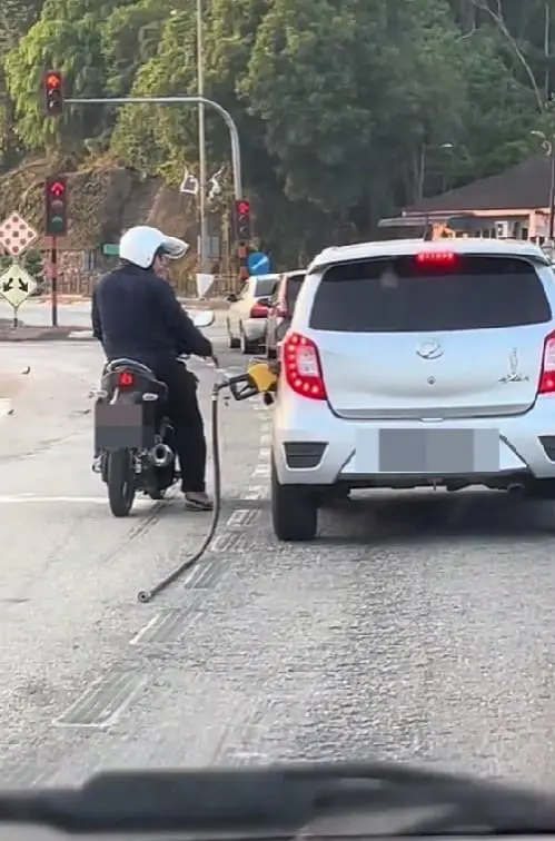 a man informing the car's owner about the hanging nozzle