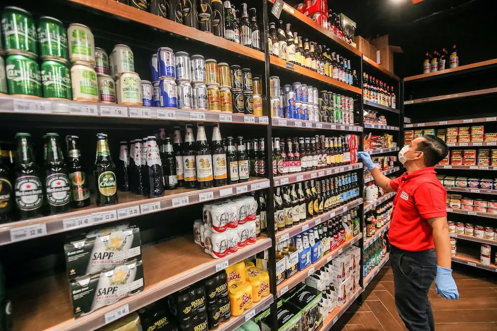 M'sian store worker looking at a rack displaying alcohol