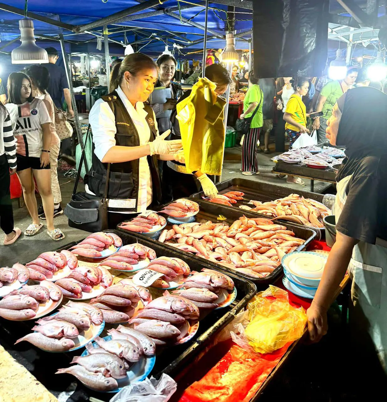 authorities talking to a fish seller at a night market at sabah