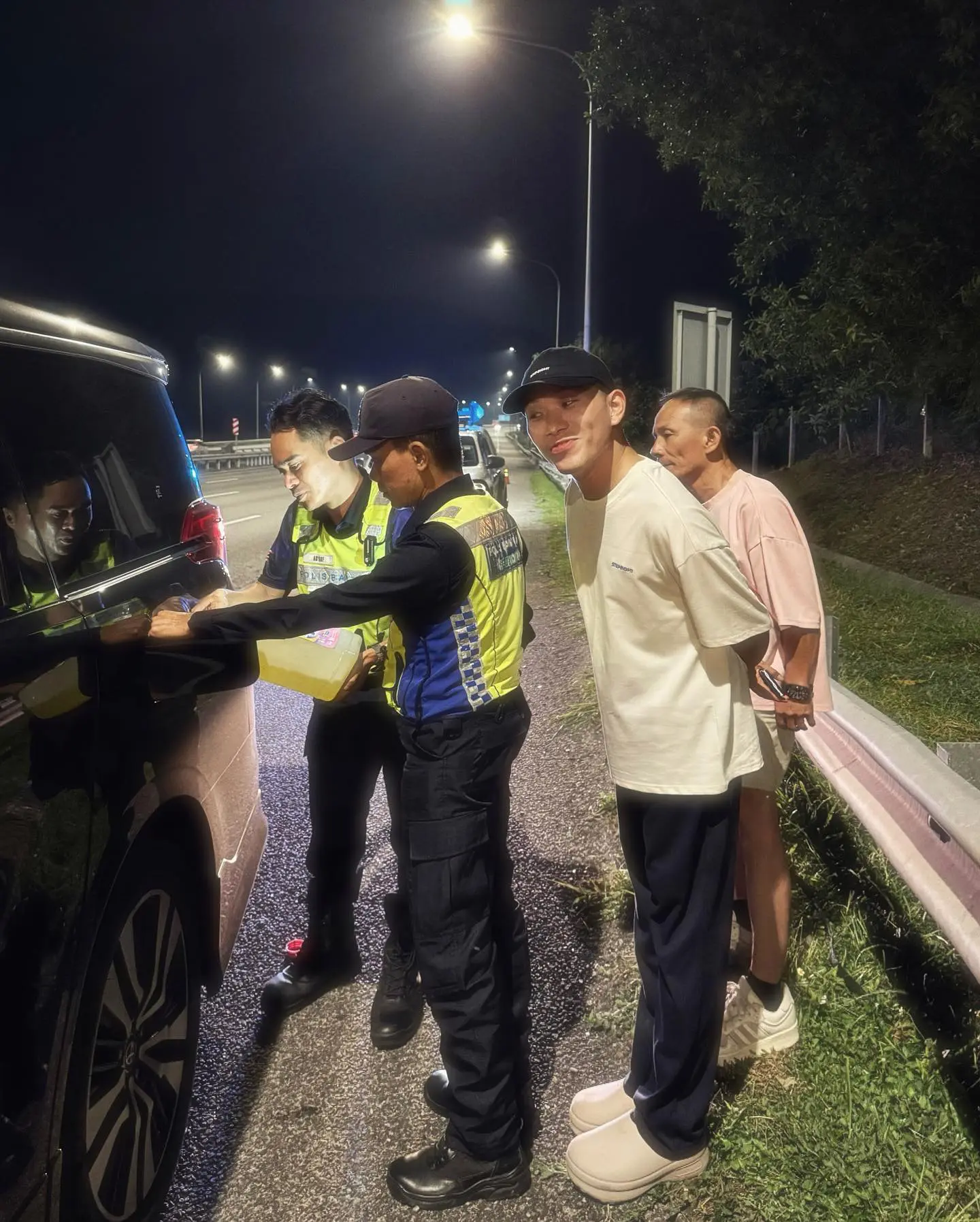 auxiliary police helping to refuel a malaysian's car