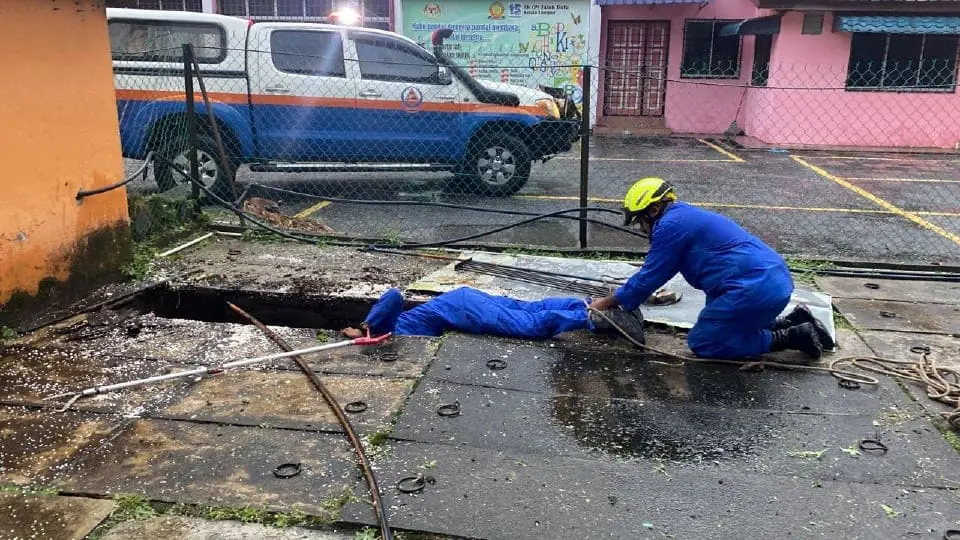 Malaysia Civil Defence Force officers looking for a man who fell inside the drain