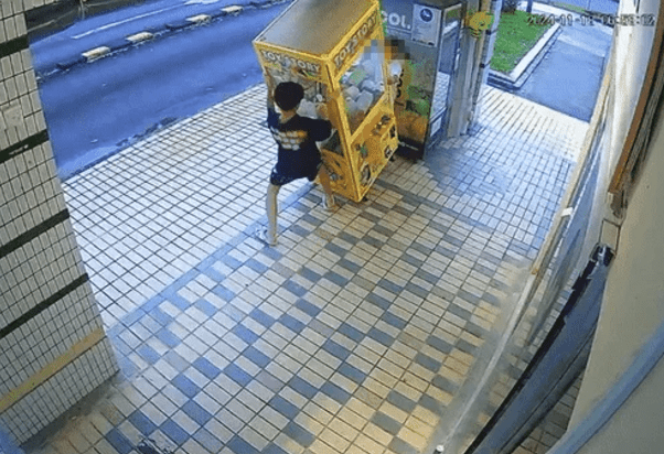 Boys trying to tip Labubu claw machine over
