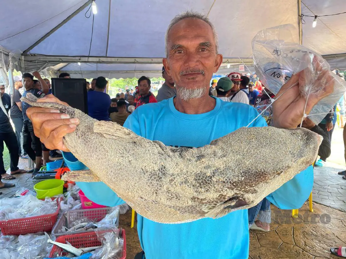 msian man showing the pufferfish that he caught