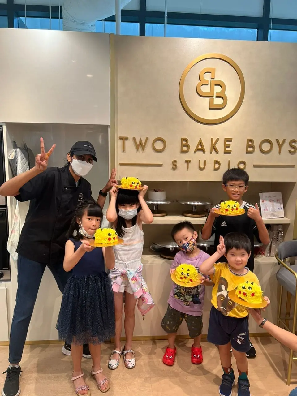 children showing their pikachu cake they did with the guidance of baker