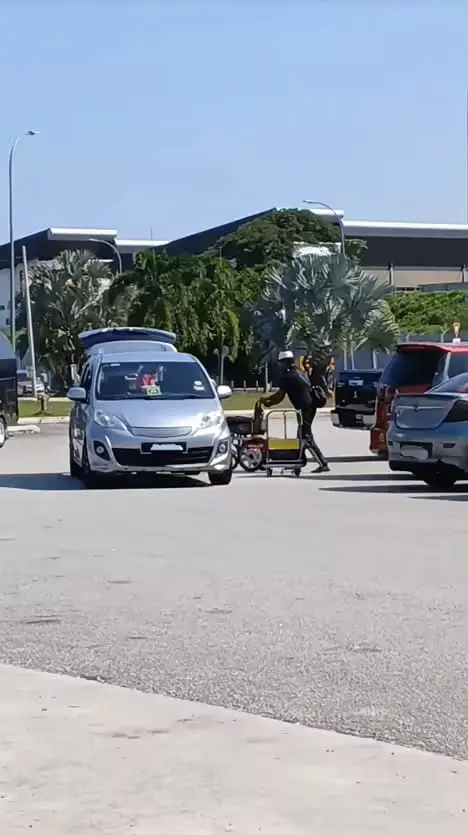 'Disabled' rendang seller pushing wheelchair to car
