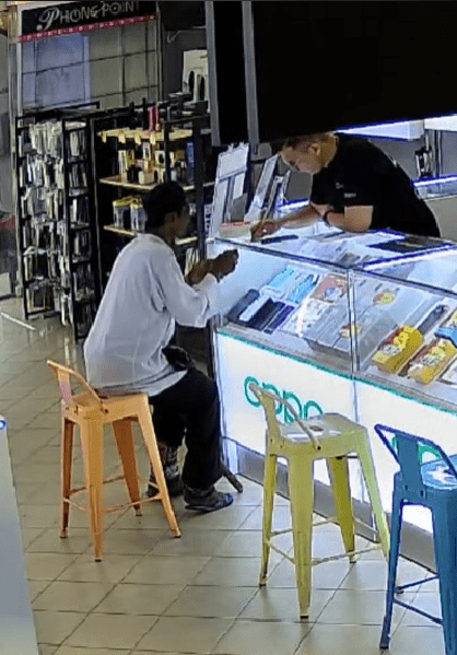 elderly man talking to a man working in a phone shop