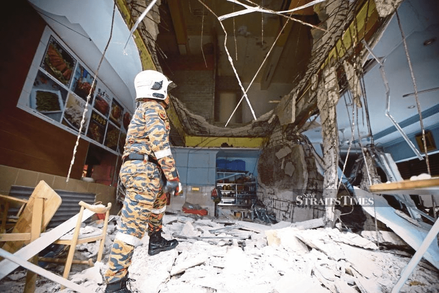 Firefighter looking at collapsed ceiling at Kompleks Segama