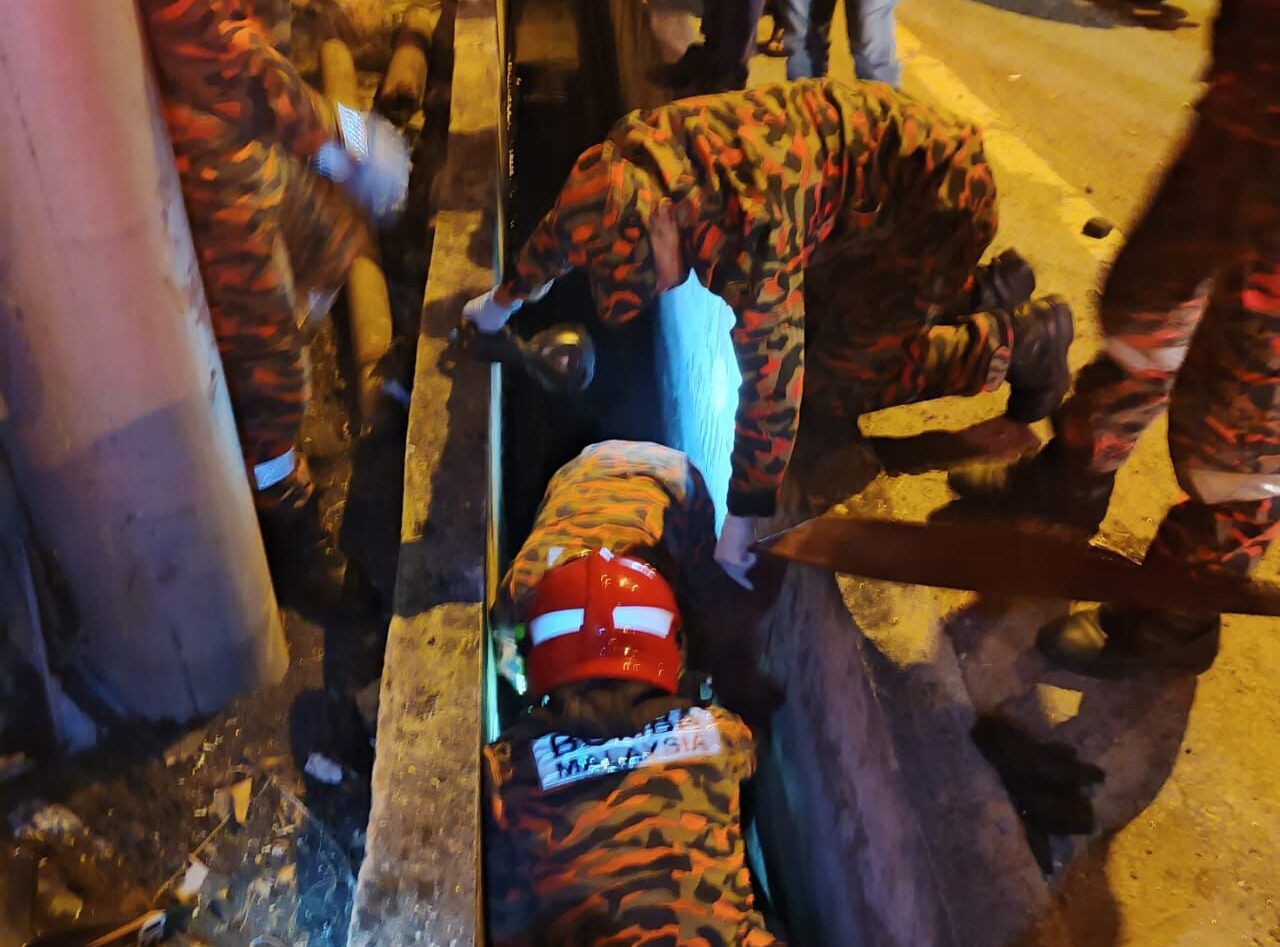 Firefighters carrying body of man from drain in Penang