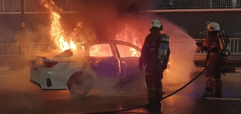 Firefighters extinguishing the fire of burning Toyota Vios
