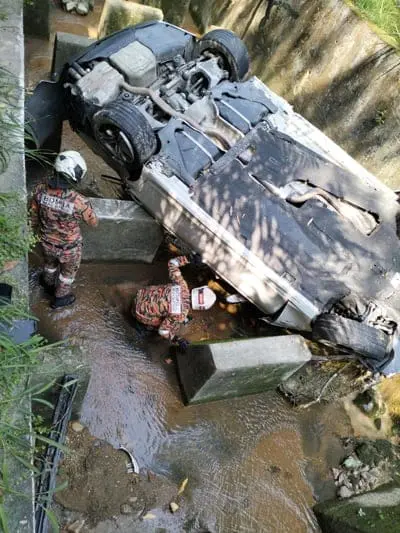 Firefighters inspecting Lew Wei Chee's car
