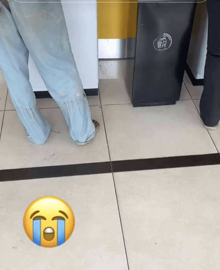 Foreign Worker removes shoes at ATM 01