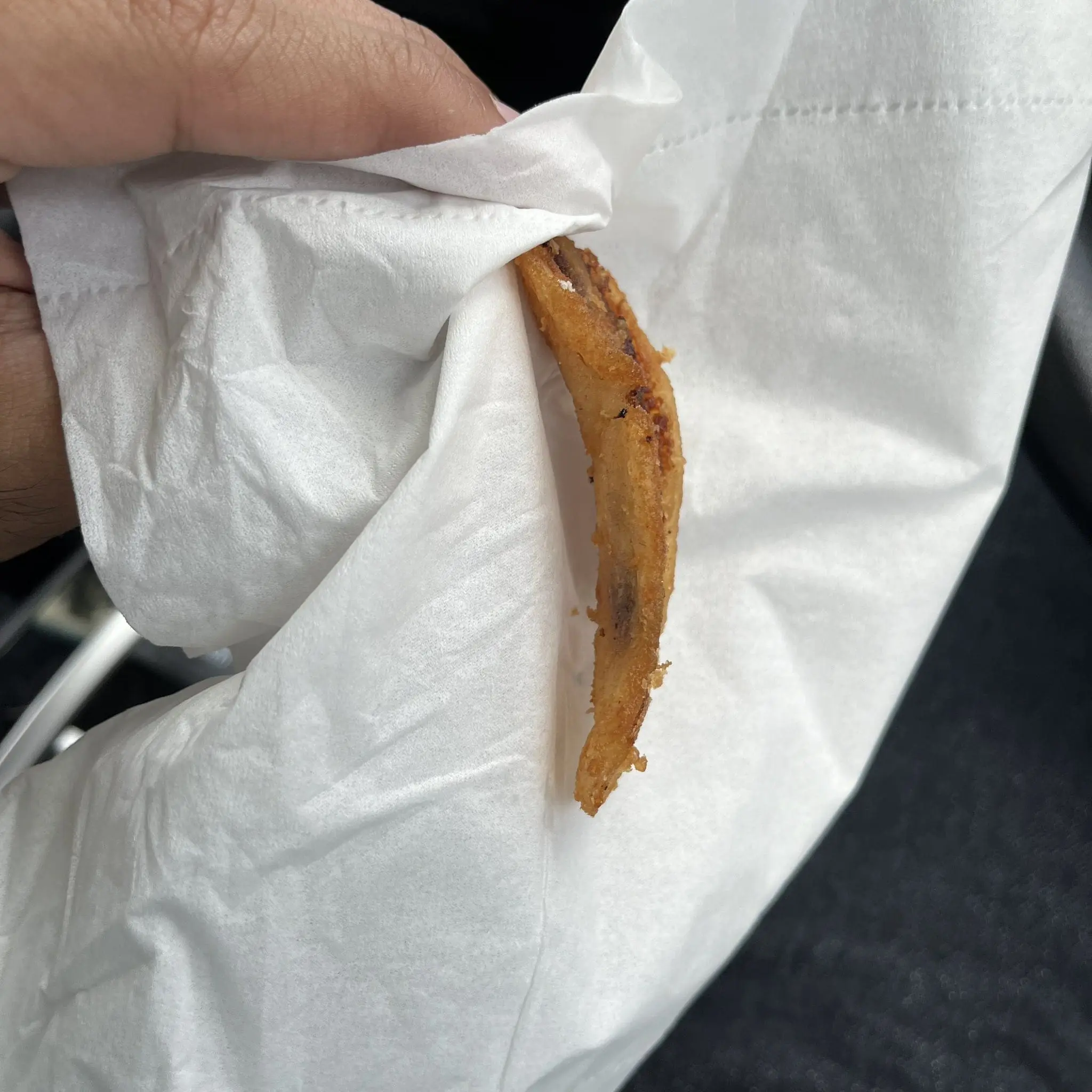 Msian is showing the tiny-sized banana fritters that he bought at a roadside stall.