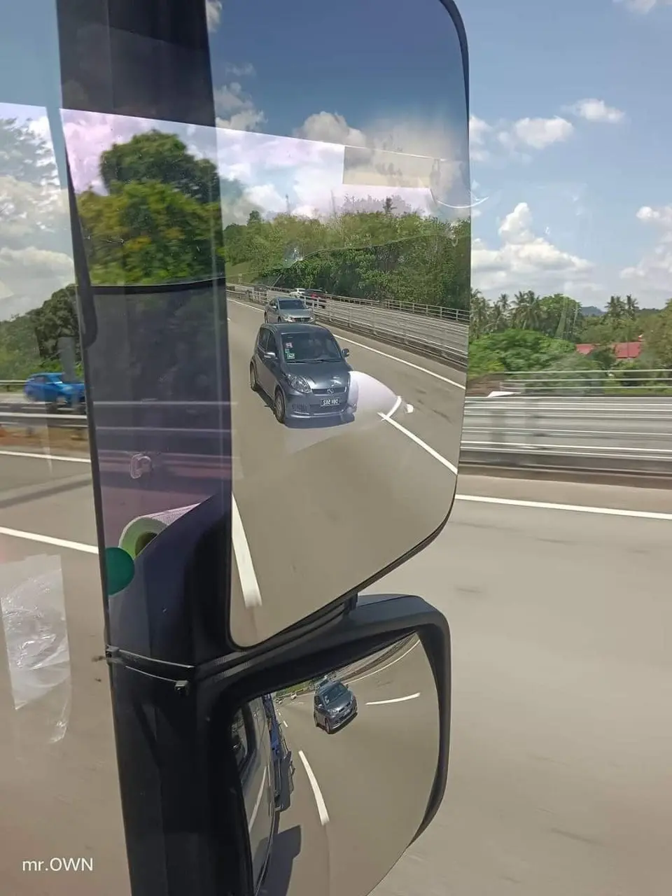 Bus' side mirror shows Myvi coming beside it