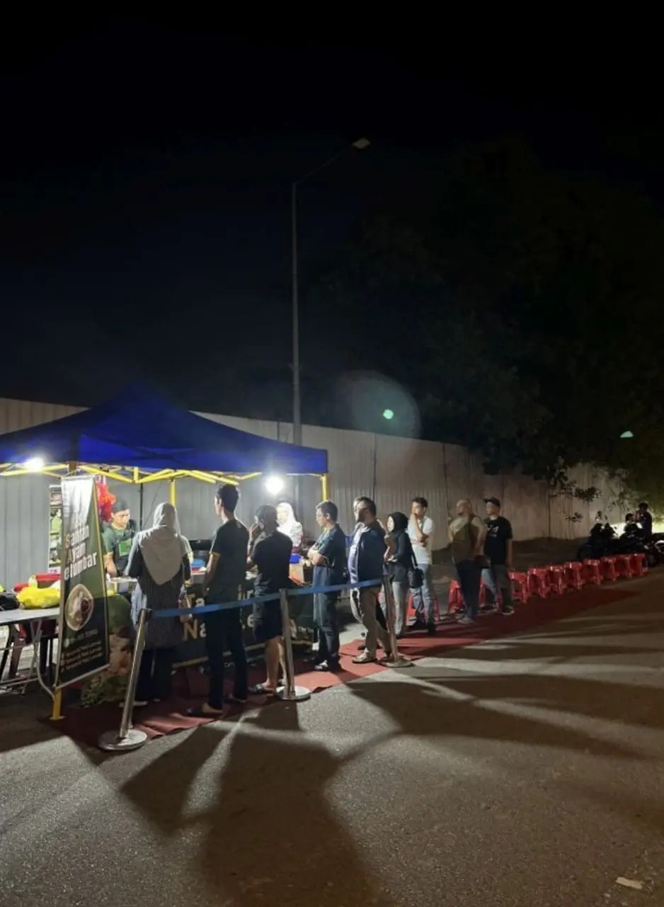 People waiting in line on a red carpet to buy street side food