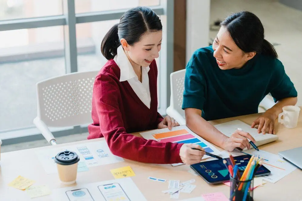 2 Asian women discussing at the office