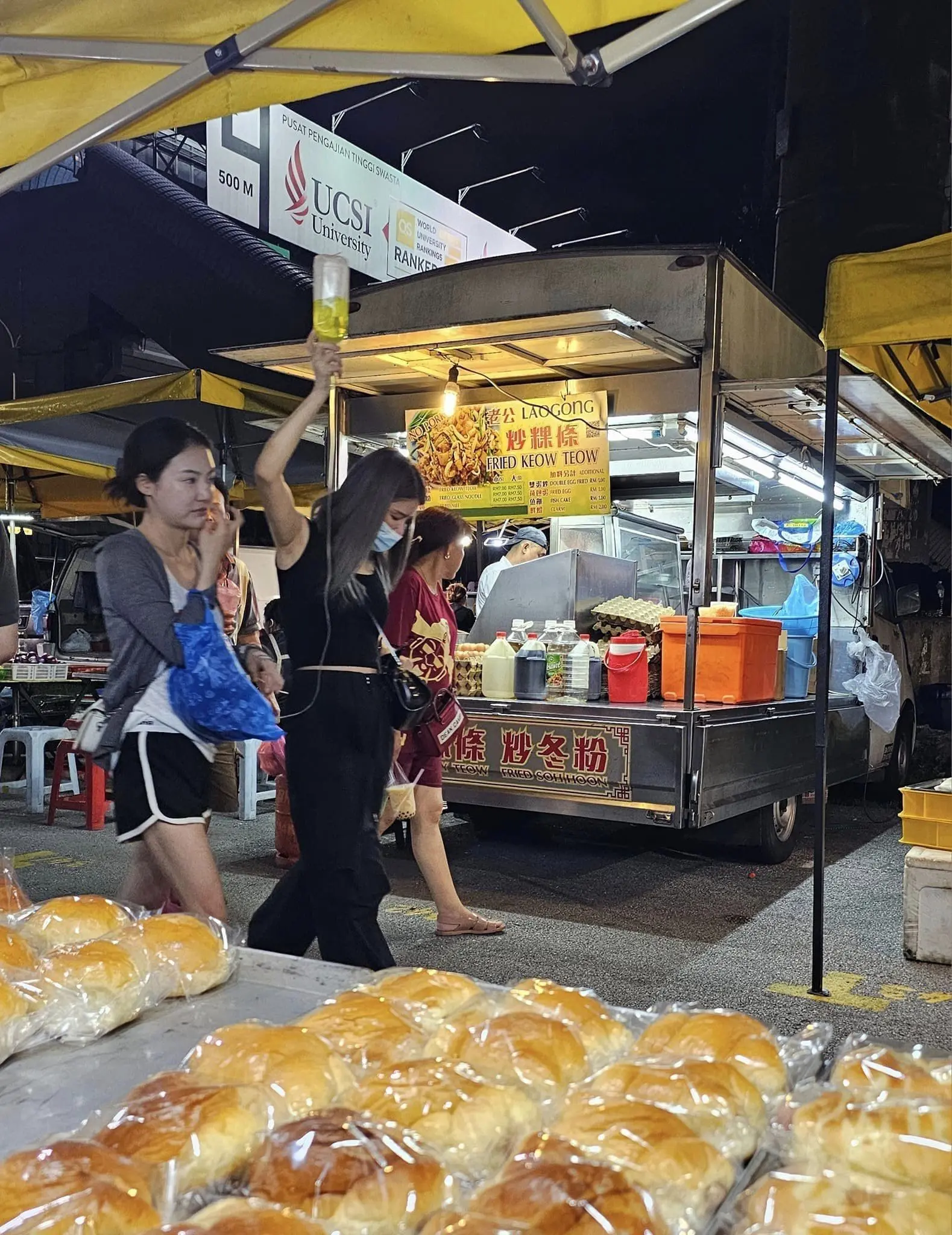 Woman visits Taman Connaught night market along with IV drip