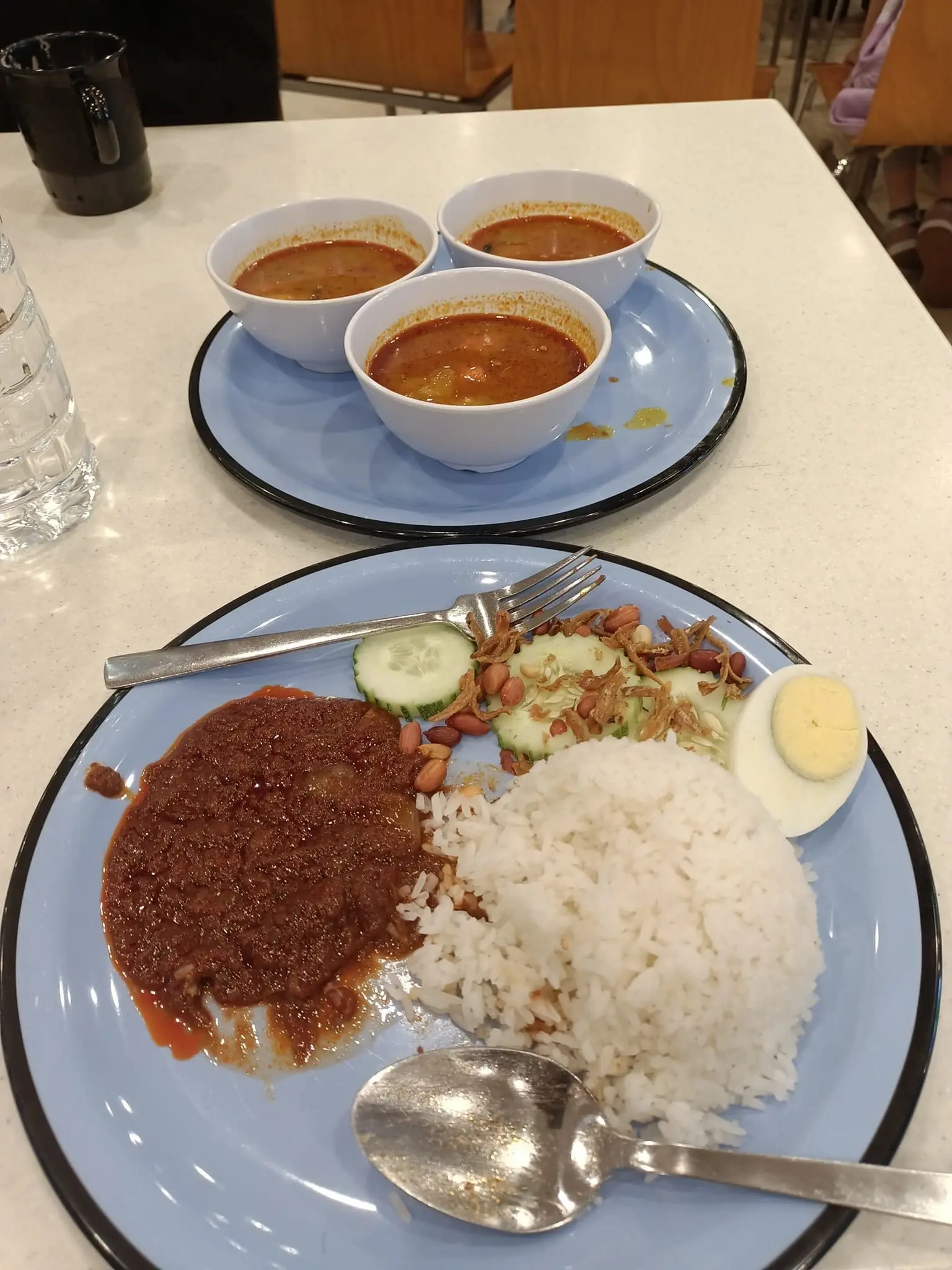 A plate of nasi lemak and 3 bowls of curry