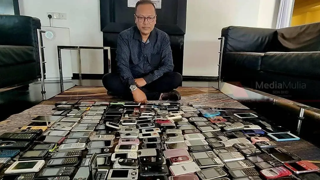 msian man showing his collection of old phones