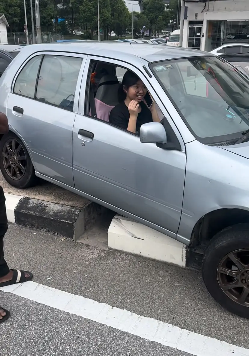 driver smiles after car gets stuck on road divider