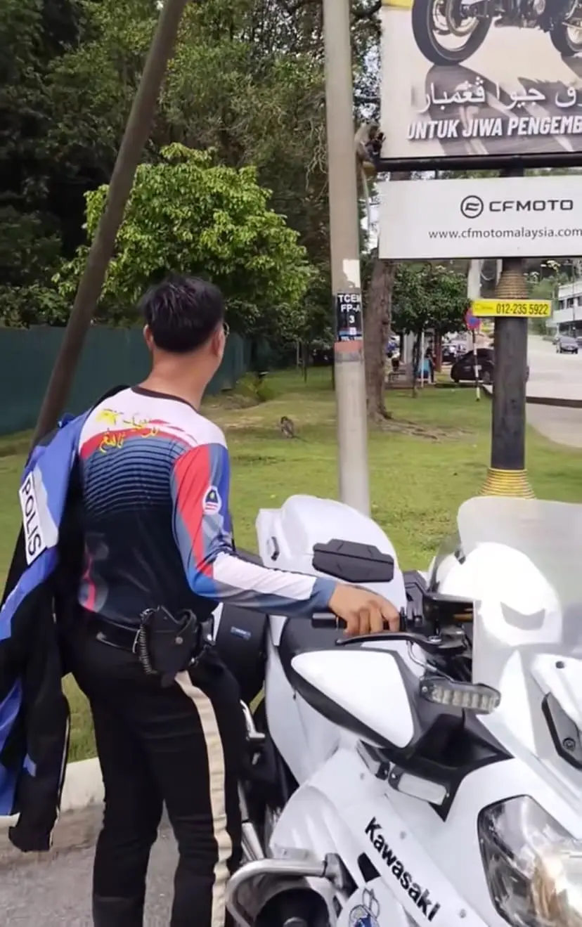 PDRM officer steps out of his bike to look at the monkey that stole his glove