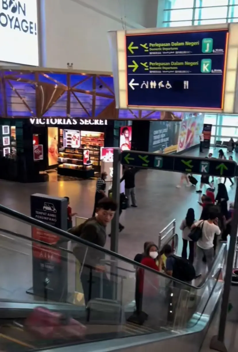 Man standing on escalator with luggage by his side in KLIA2 and collided with another luggage 