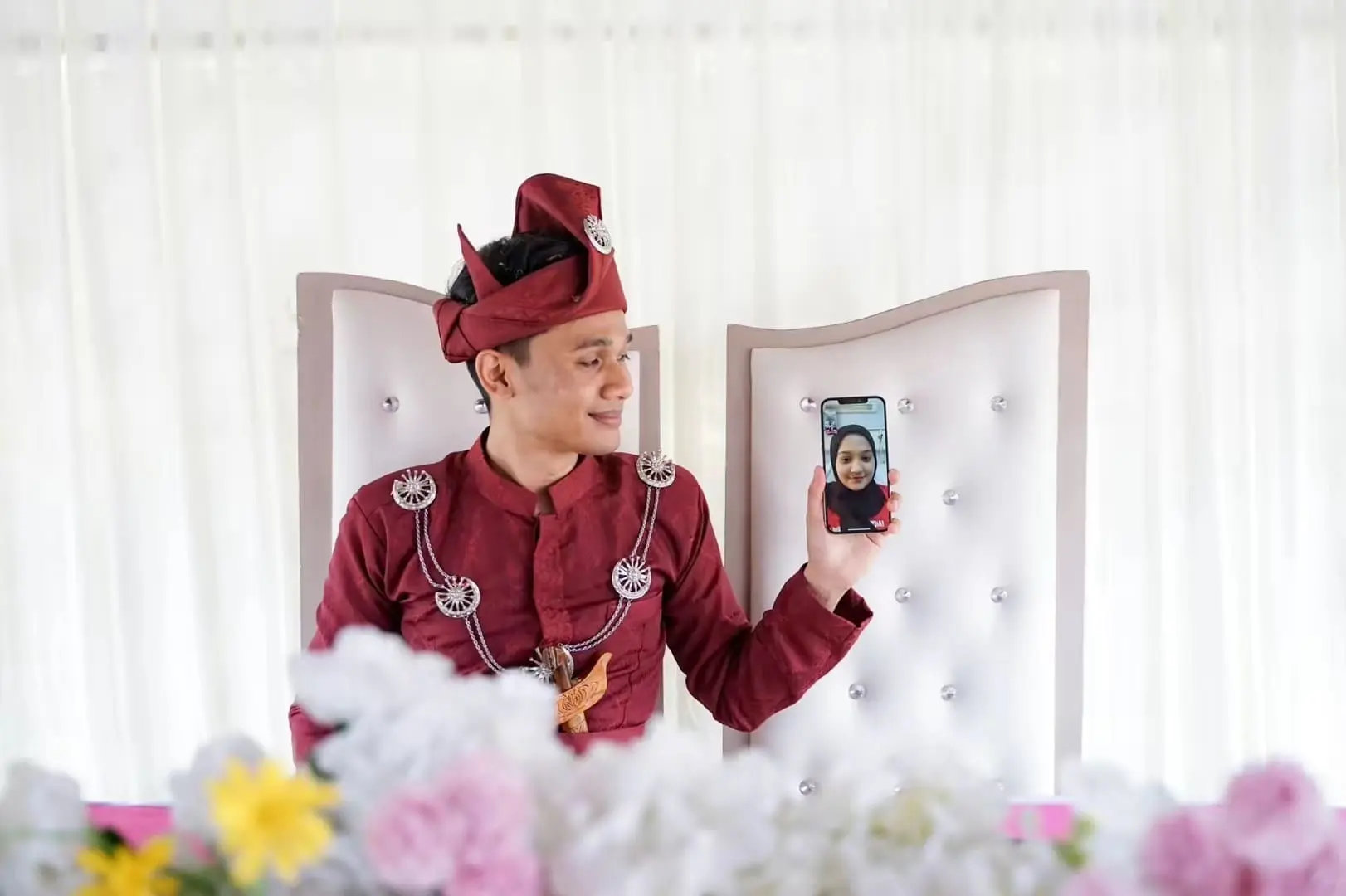 Malay man in a wedding ceremony holding a phone while video calling his wife who got hospitalised