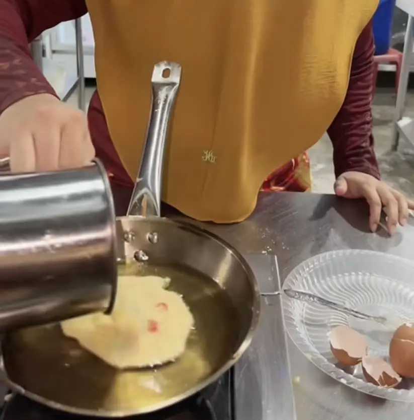 Malaysian woman frying egg 