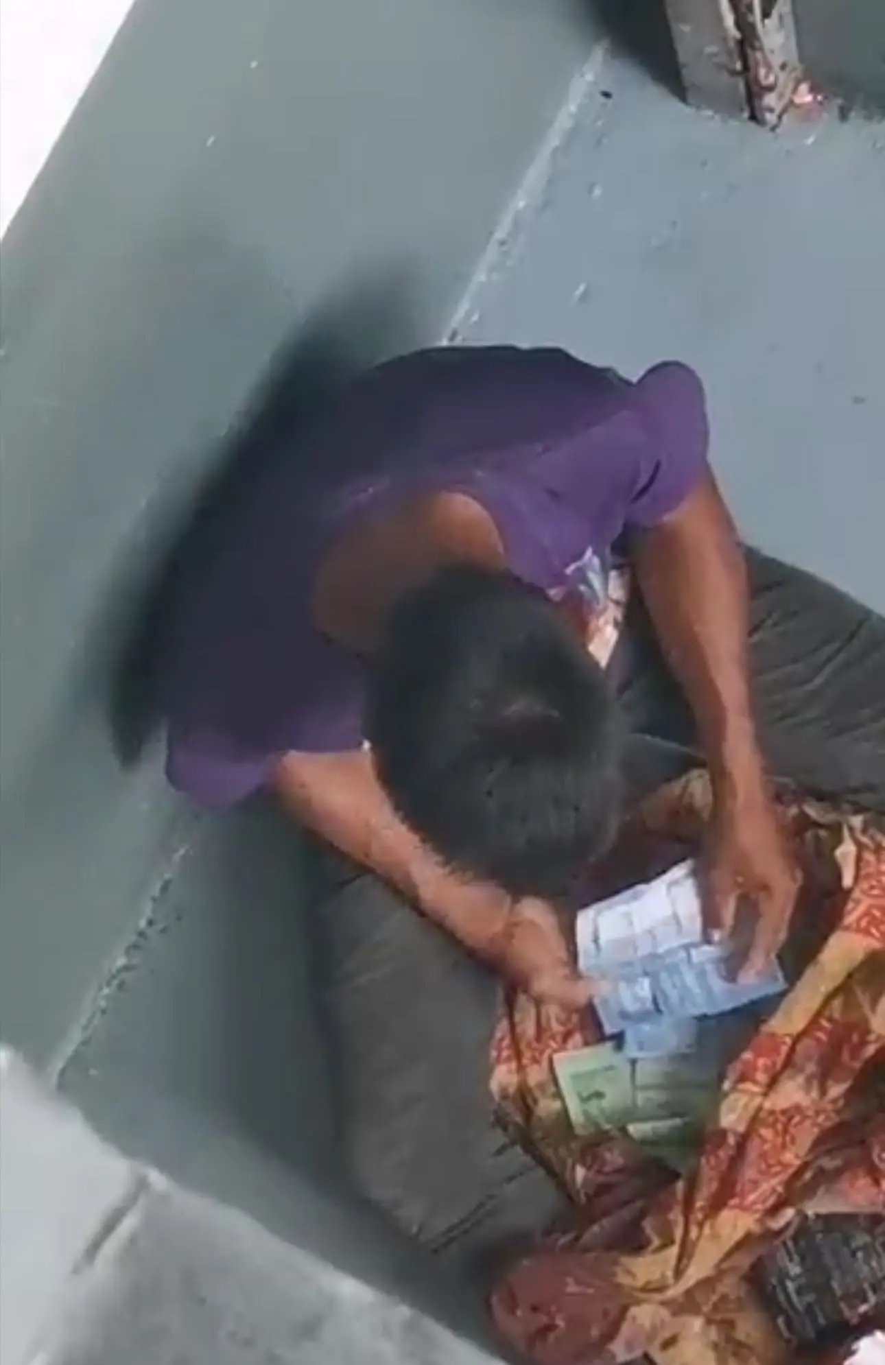 A beggar sitting while counting his earnings of the day