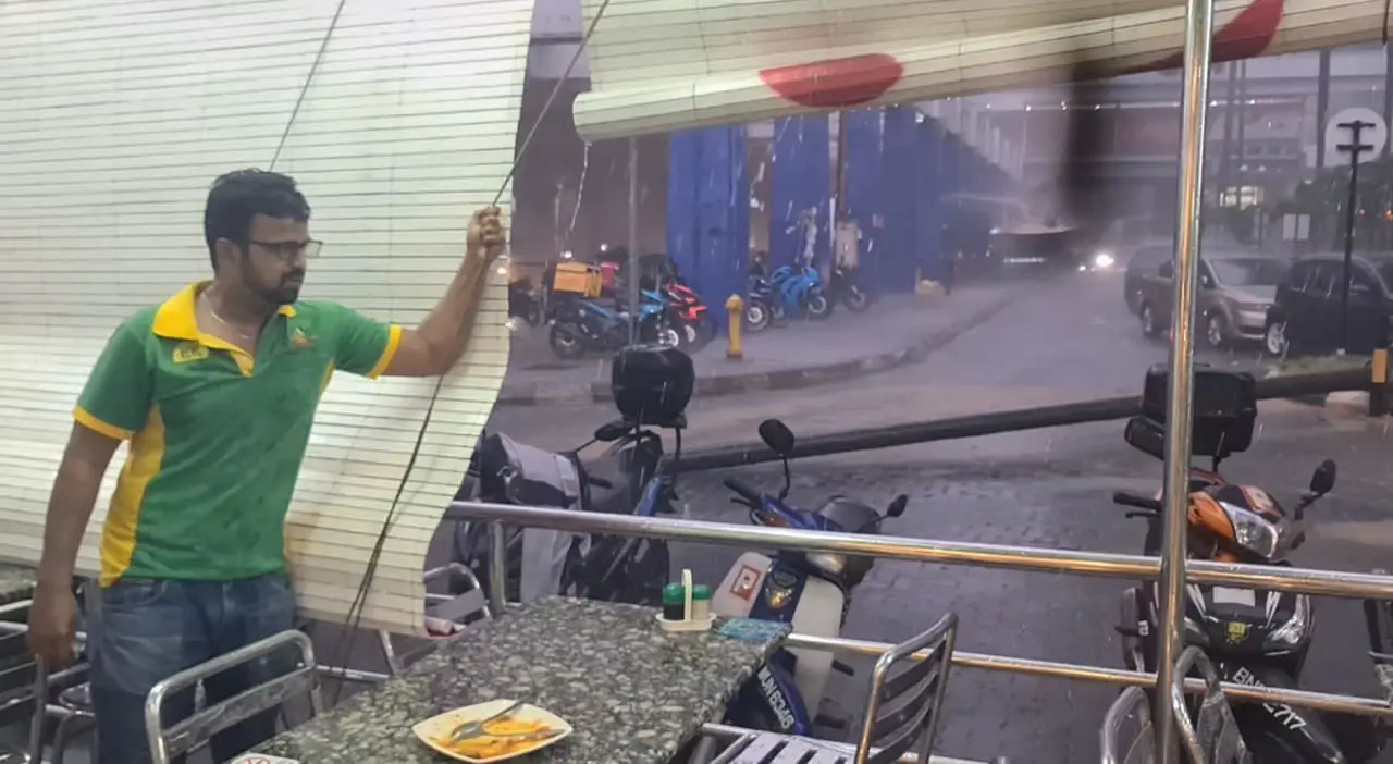 Nasi kandar worker holding the curtain to make sure the rain doesnt affect the customers 