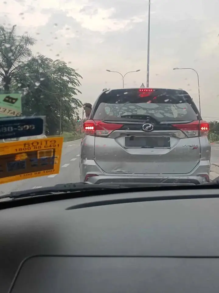 Young M'sian boy sticks body out from car