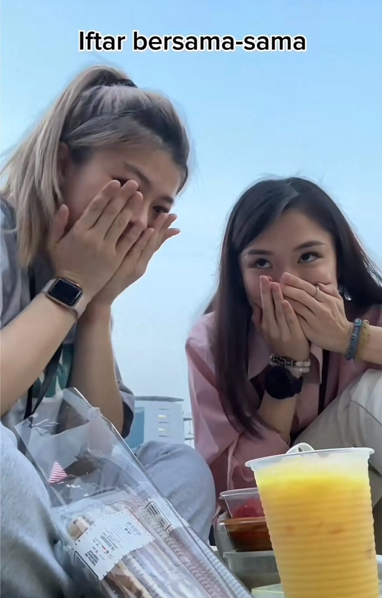 Two chinese women pray alone with other muslims at Putrajaya Square