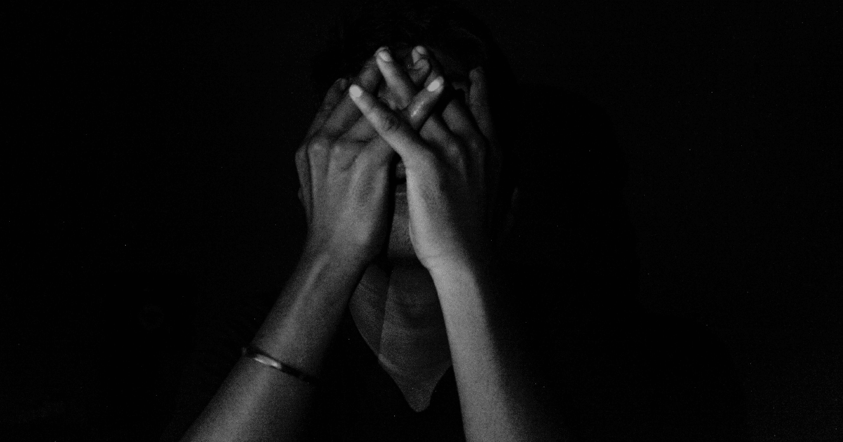 person in dark background seemingly stressed 