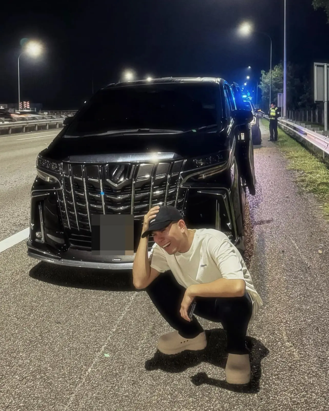 Malaysian content creator Phei Yong squatting infront of his car