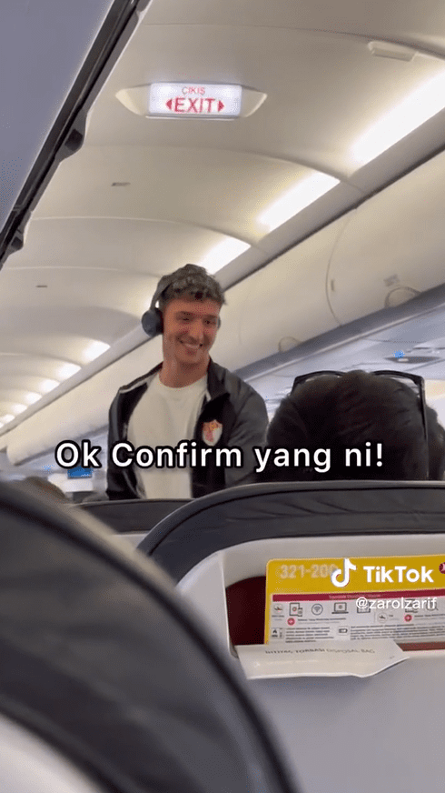 Handsome Turkish man walks down aircraft aisle