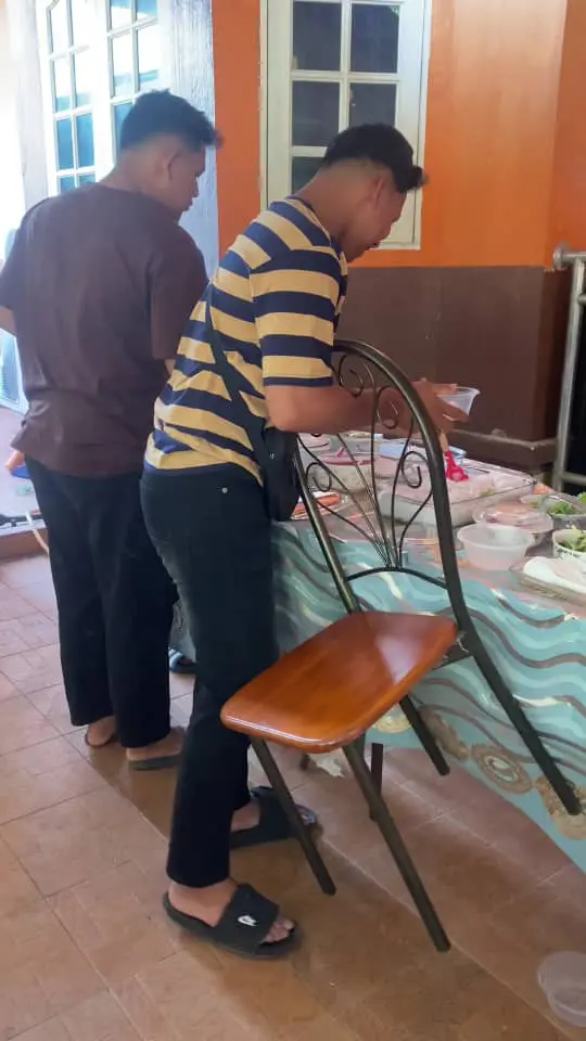 man carries chair in his arm while takig food