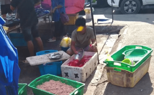 man caught adding red coloting agent into a box filled with fish