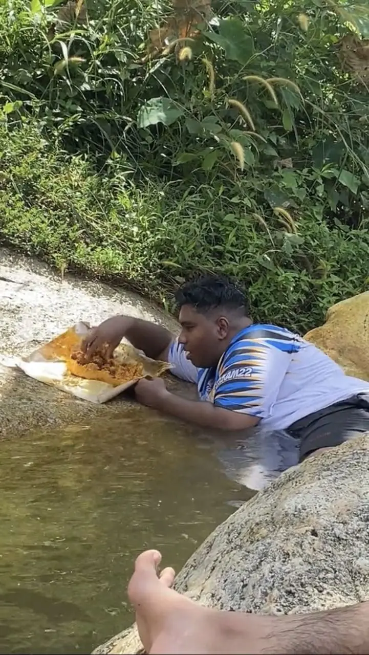 M'sian man eats nasi campur while submerged inside a river