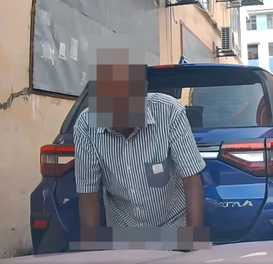man pooping in between two parked cars