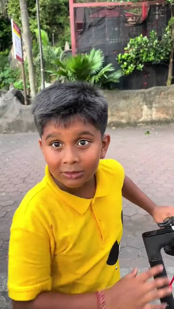 Msian boy talking to a man while riding his scooter