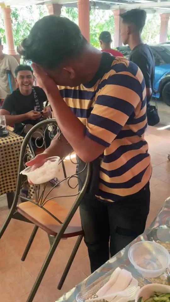 msian man laughing while carrying food and chair