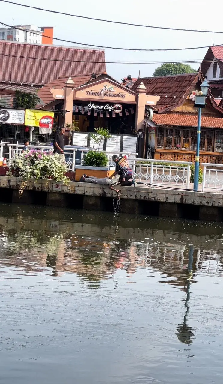 msian man pullingout gray cat trapped in malacca river