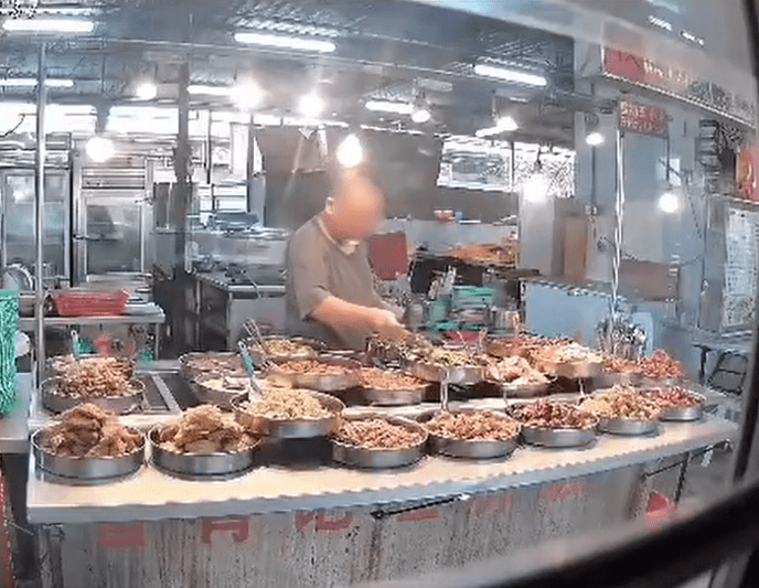 M'sian mixed rice stall owner tastes dish with spoon