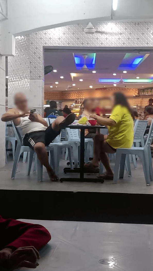msian uncle puts his foot on the table at mamak restuarant