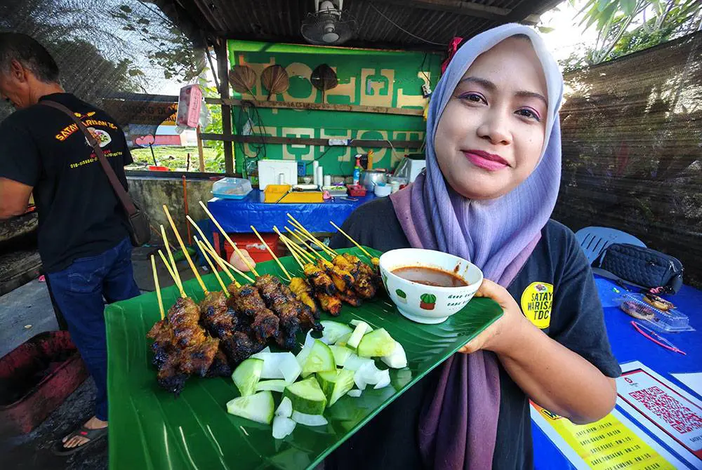 msian woman showing a plate full of satay