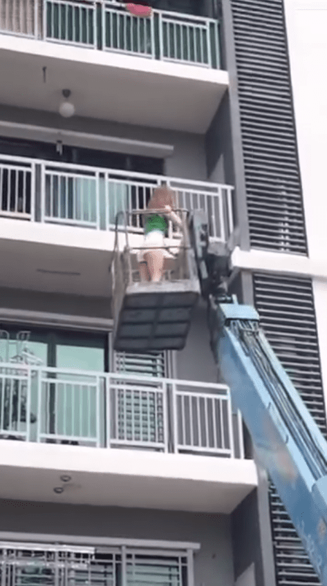 msian woman using crane to enter her home through balcony