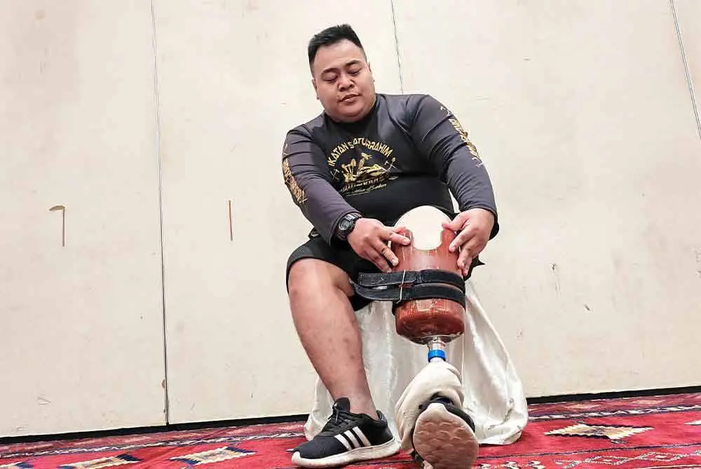 Muhammad Azizi showing his prosthetic leg